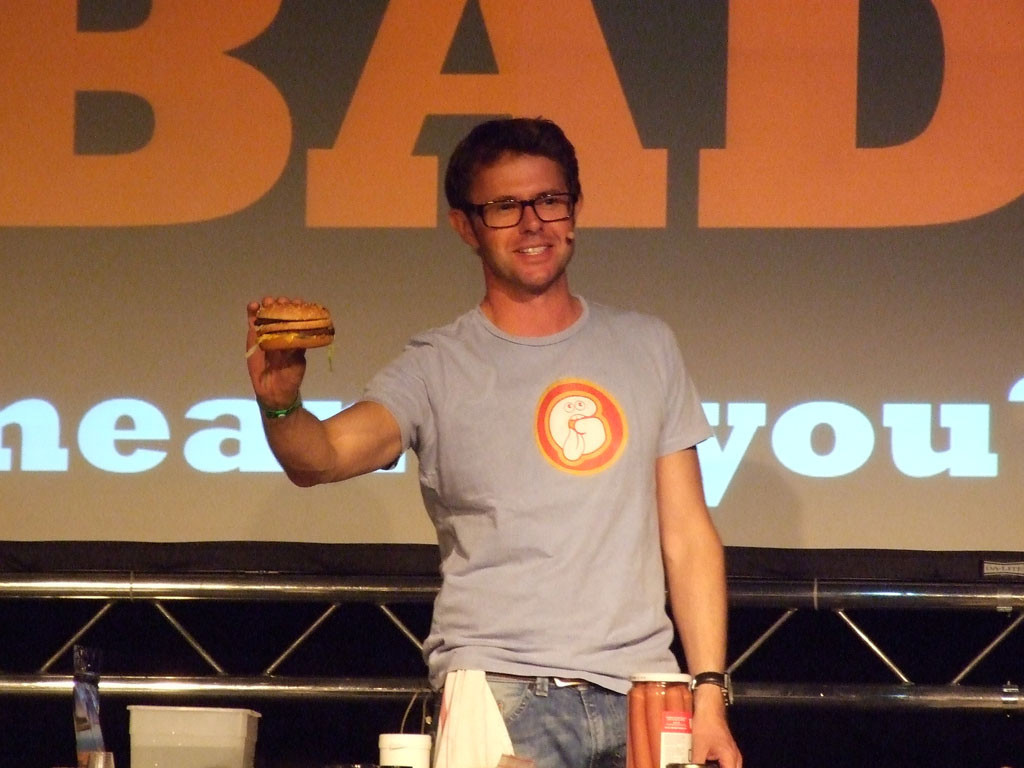 Stefan Gates at a live event with a Big Mac, discussing on the definition of "bad" food. He then went on to skin (and presumably cook) a pig's testicle. Yum. Image by Nelson Cunnington.